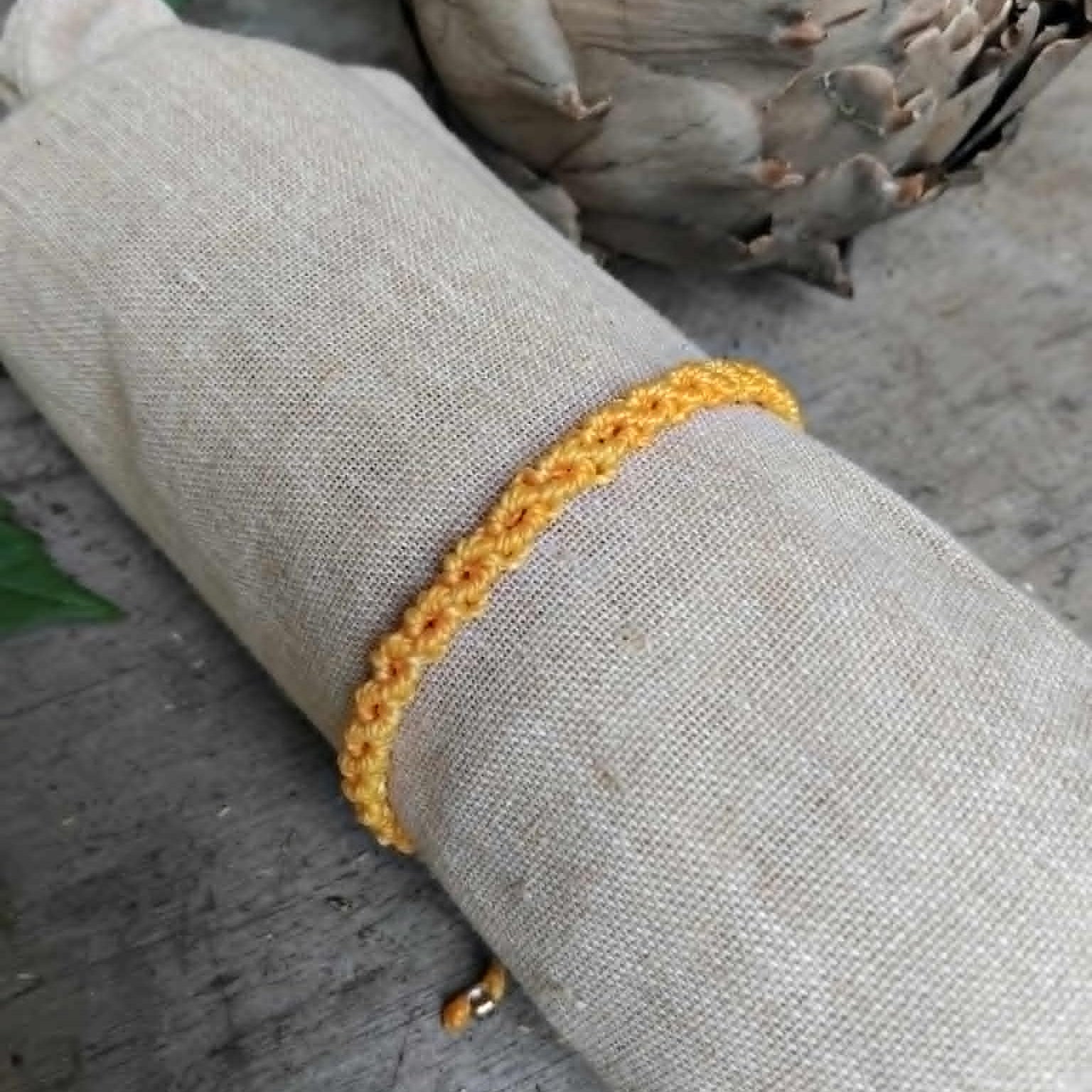 A handcrafted macrame knotted bracelet in yellow waxed cord.