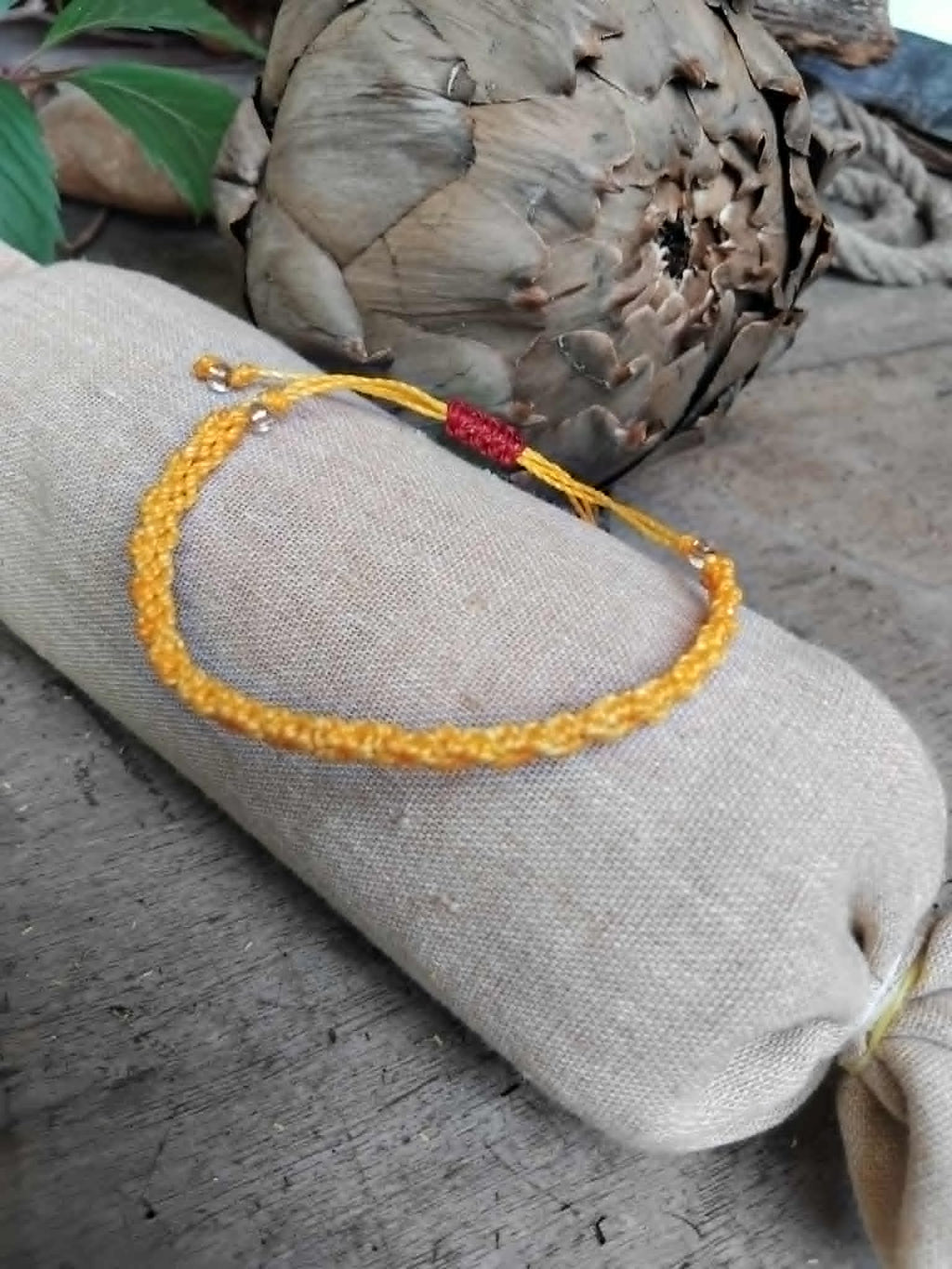 A handcrafted macrame knotted bracelet in yellow waxed cord.