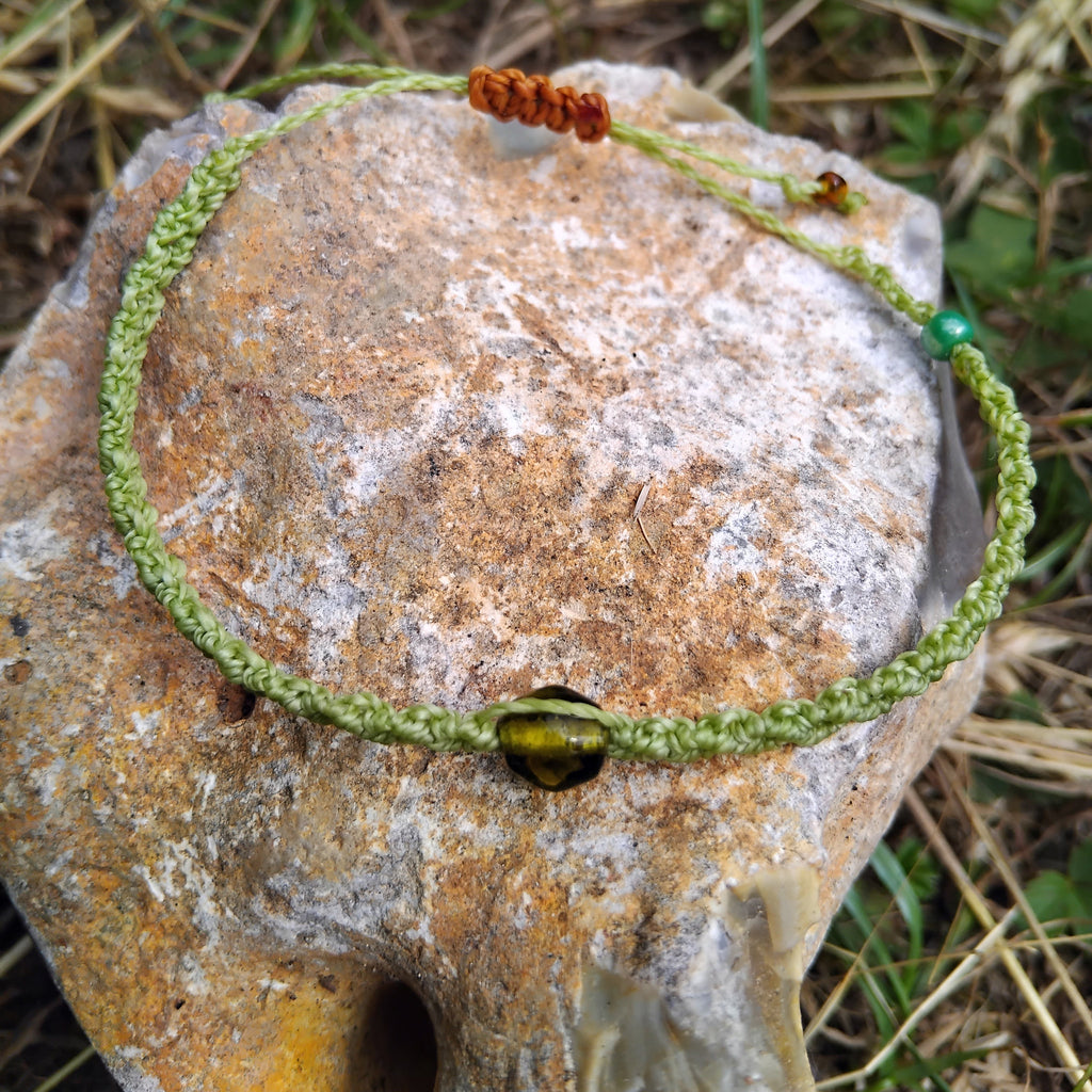 Green macrame bracelet on a textured stone surface with natural background