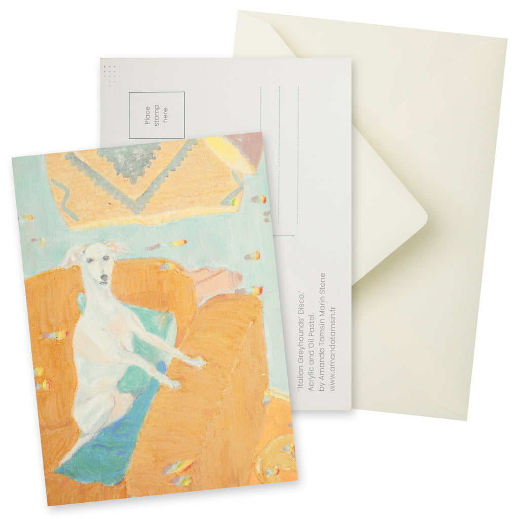 Postcard with a painting of a greyhound dog sitting in an orange-beige armchair with blue and green cushions.  Background (wall) is pale blue with a tapestry and mauve lamp.  Another dog is leaving the scene.  Includes the reverse of the postcard and a cream envelope.